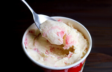 Closeup of spoon scooping delectable strawberry cheesecake ice cream - obrazy, fototapety, plakaty
