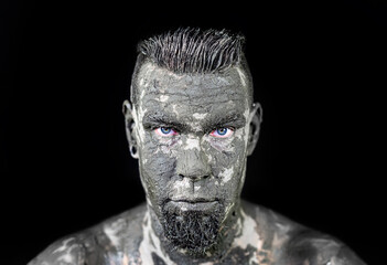 Gesicht eines Mannes ist mit Schlamm bedeckt - Face of a man is covered with mud. Dark evil man celebrates music.
