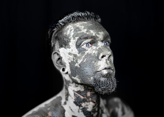 Gesicht eines Mannes ist mit Schlamm bedeckt - Face of a man is covered with mud. Dark evil man celebrates music.