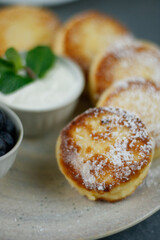 Cottage cheese pancakes (ricotta fritters) with frozen berries and yogurt on blue plate. Healthy morning breakfast or snack, dietary food. White background.  Close up view.