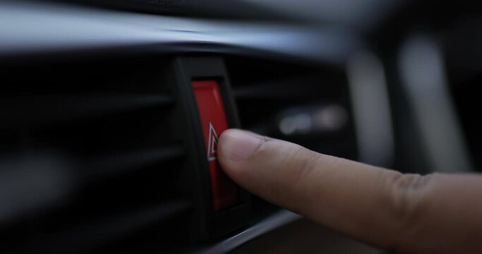 Close up of Man pressing car hazard emergency lights button in car motor. Car warning lights after breakdown accident. Car service concept.