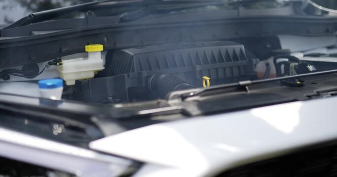 Close up side view of Car engine is starting to smoke and burn. Man open the hood. Car service concept.