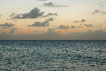 Horizontal Background of the sea with an orange and cloudy sunset with a dark sea and no waves