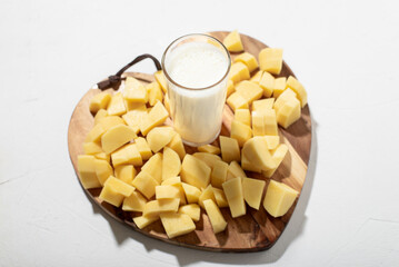 Potato milk concept. Alternative milk. A glass of milk on a wooden board with chopped raw potatoes.