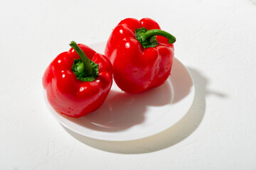 Two bell peppers on a white plate. White background. Vegetarianism, vegetable concept.