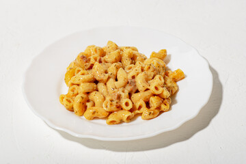 curly pasta with sauce on a white plate. Minimalism. White background. Pasta in cheese sauce.