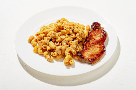 Figured Italian pasta in sauce. Pieces of chopped fried meat. Minimalistic food design. White background.