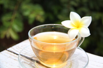 Jasmine tea, delicious and a clear glass cup with a jasmine flower, on a wooden table, outdoors, top view.