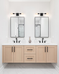 A modern bathroom with a wooden vanity cabinet, black faucets, white marble countertop, and black...