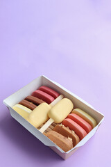 a box with popsicles of different flavors: strawberry, raspberry, chocolate, mango, caramel, lemon, pistachio