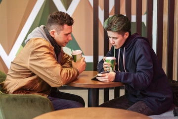 A guy and a girl are sitting in a cafe and using smartphones. Communication, technology, internet.