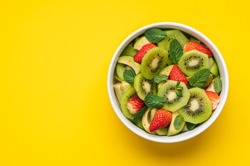 Fresh fruit salad with kiwi, avocado, strawberries and mint in bowl. Multi-colored ripe fruits and berries