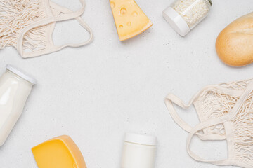 Cheeses, bottle of milk, jar of yogurt, cottage cheese, bread, mesh bags on gray background. Concept for grocery store, farmers market