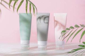 Various cosmetic tubes for serum, cream and lotion on pastel pink background. Natural cosmetics for skin care concept