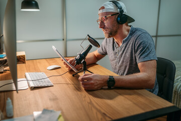 Middle-aged Blogger man in headphones reading text recording voice or making online webinar or news...