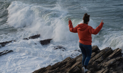 chica en la costa viendo romper las oas