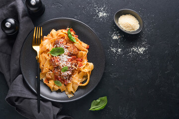 Tagliatelle pasta with meatballs in tomato sauce, basil and parmesan cheese on black stone or concrete background. Traditional Italian dish and cuisine. Top view with copy space.