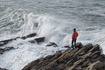 chica en la costa viendo romper las oas