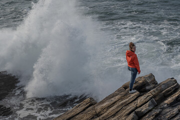 Obraz premium chica en la costa viendo romper las oas