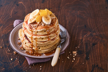 Pancakes. Homemade fluffy pancake with banana, walnut and caramel for breakfast on dark wooden background. Delicious pancakes for traditional American breakfast. Selective focus. Mock up.