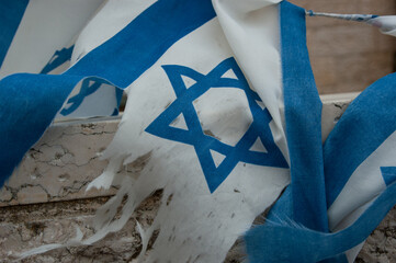 Closeup of the blue Star of David on a dirty, torn and shredded flag of the State of Israel.