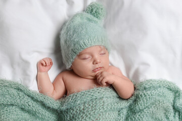 Cute little baby sleeping under knitted plaid in bed, top view