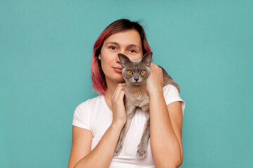 Young woman holding a gray cat in her arms