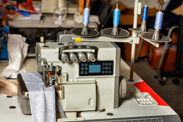 Professional overlock machine in the sewing shop of a factory for sewing clothes. Closeup.