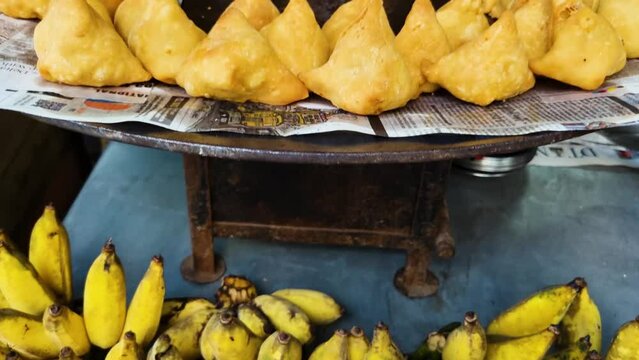 panning reveal shot going from small coastal banana to samosa pockets a fried indian fast food street food being fried in a large pot of oil