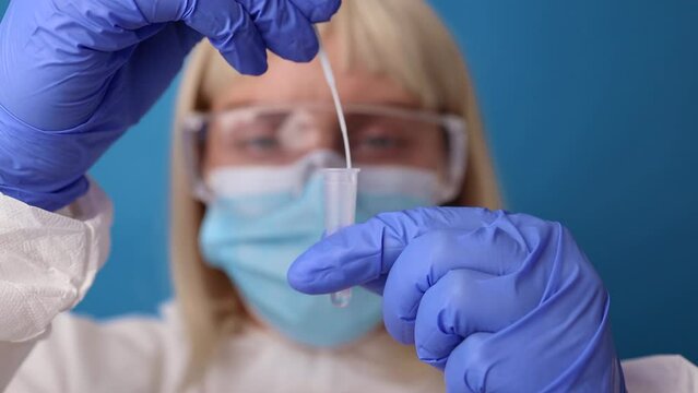 Covid 19 pcr test. Doctor in protective suit medical mask gloves holding Swab saliva sample for diagnostic covid 19 coronavirus virus in lab.