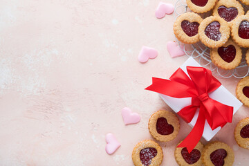 Traditional Linzer cookie with strawberry jam and powder sugar, gift and red ribbon on pink beautiful background. Top view. Traditional homemade Austrian sweet dessert food on Valentines Day.