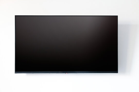 TV blank flat screen on white wall background. Black empty television display front view, copy space