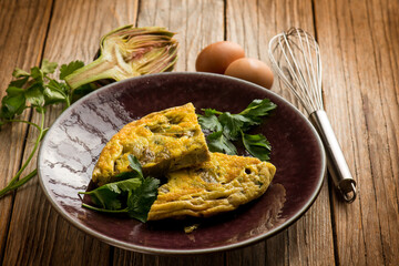 slice omelet with artichoke over wooden table