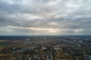 Fototapeta na wymiar Aerial view of rural homes and distant high rise apartment buildings in city residential area during cloudy weather