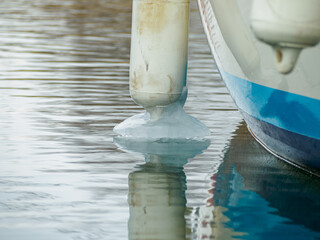 Icy white fenders suspended between a boat and dockside for protection. Maritime fenders in winter.