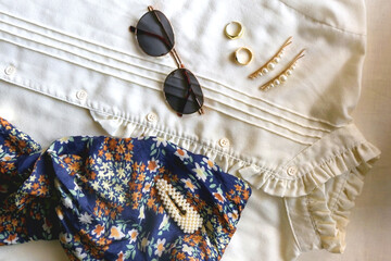 Vintage white blouse, floral scarf, round sunglasses, gold rings and pearl hair barrettes. Flat lay.