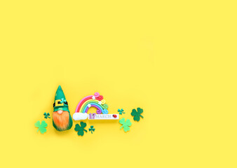 cute irish gnome, rainbow toy, clover leaves, 17 march date calendar on bright yellow background. symbol of Saint Patrick day, traditional irish holiday. flat lay. copy space