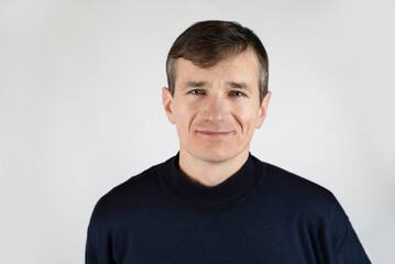 Fototapeta premium Mature slender man smiling on a light background, hair begins to turn gray, man is happy, not afraid of the crisis of middle age