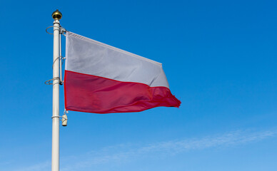 Flaga Polski powiewająca na tle nieba. Symbol narodowy.