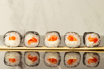 Sushi rolls with salmon, lie on wooden sticks on a light background