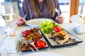 baked trout with grilled vegetables and shrimp and fresh lettuce on a white plate, food and delicacies