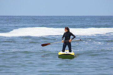 Young woman paddling on a board in Punta Hermosa, Peru