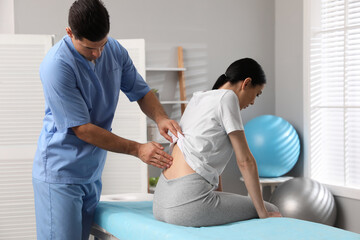 Orthopedist examining woman's back in clinic. Scoliosis treatment