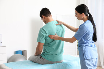 Orthopedist examining man's back in clinic. Scoliosis treatment - obrazy, fototapety, plakaty