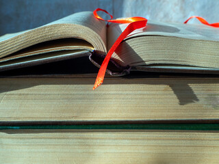 Stack of old thick books close up. Bookmark on the pages of an open book. The concept of scientific...