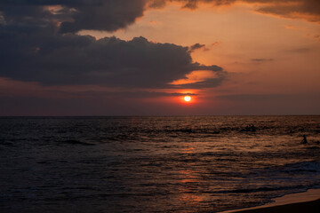 sunset on the ocean with surfers in sri lanka