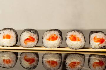 Sushi rolls with salmon, lie on wooden sticks on a light background