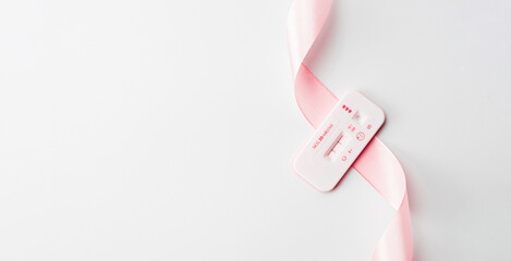 Pregnancy test kit. Positive woman pregnant test with pink silk ribbon on white background. New life and new family. Motherhood, pregnancy, birth control concept.