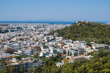 Fototapeta na wymiar Snow-white houses of Greek capital, green hills against background of sea. Athens, Greece