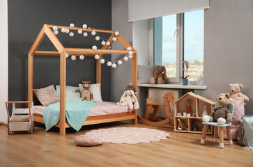 Stylish child room interior with wooden bed in shape of house and toys